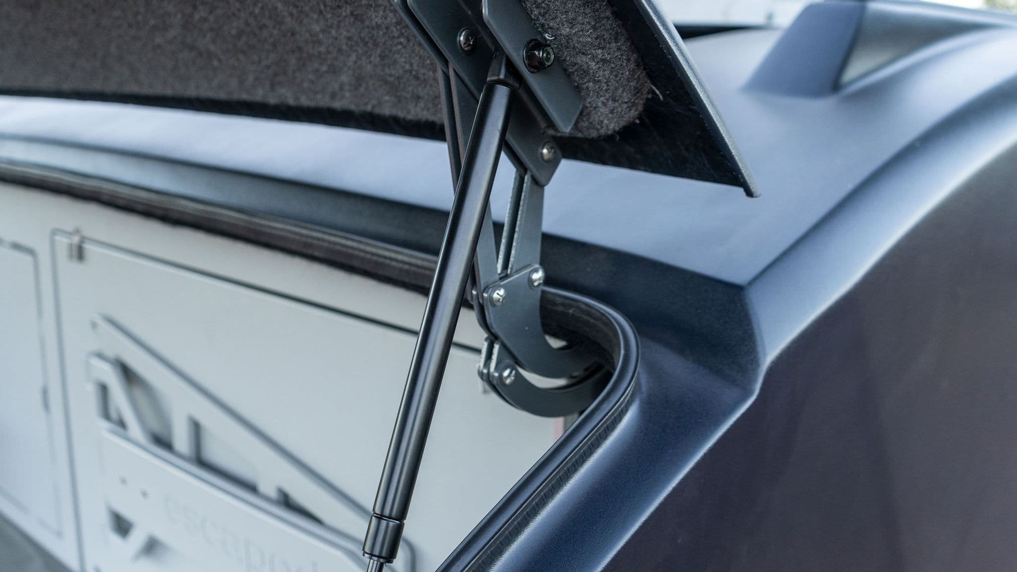 Close-up of a hydraulic hinge mechanism supporting the galley hatch of an Escapod trailer, showcasing its robust and durable design.
