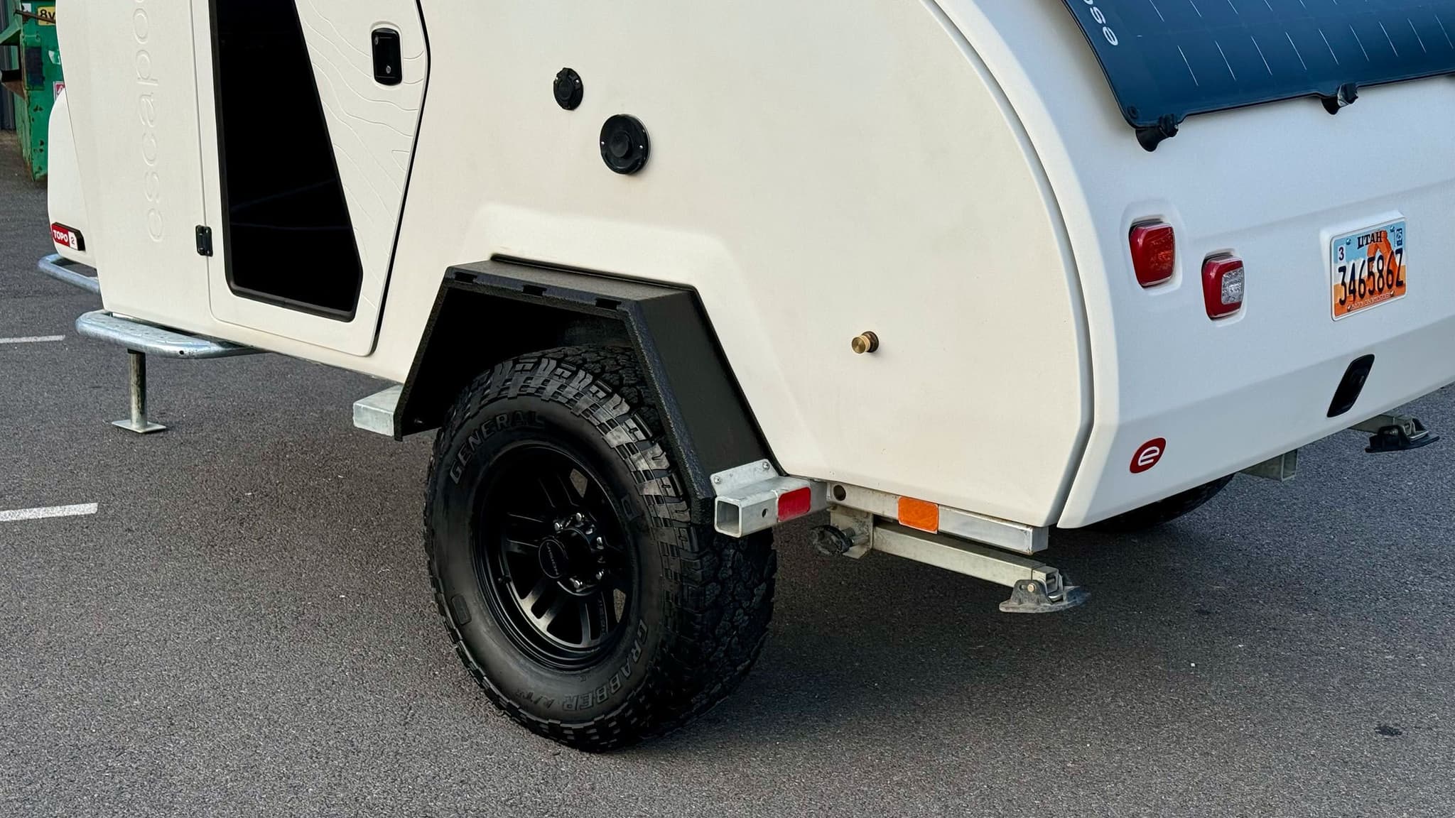 Exterior of a white 2023 Escapod TOPO2, photographed at Escapod's headquarters in Coalville, UT, with a ROAM awning and an iKamper Tent.