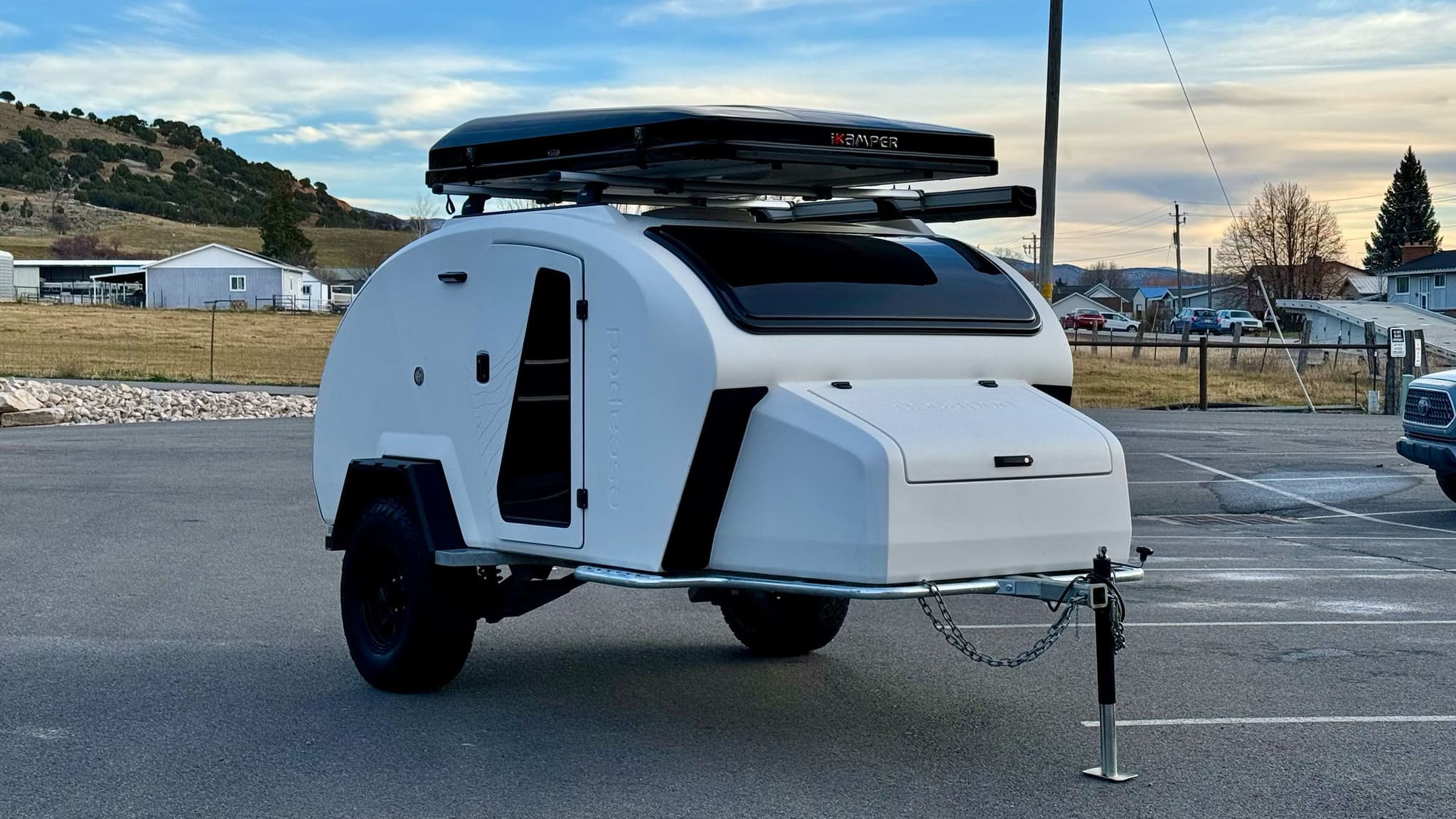 Exterior of a white 2023 Escapod TOPO2, photographed at Escapod's headquarters in Coalville, UT, with a ROAM awning and an iKamper Tent.