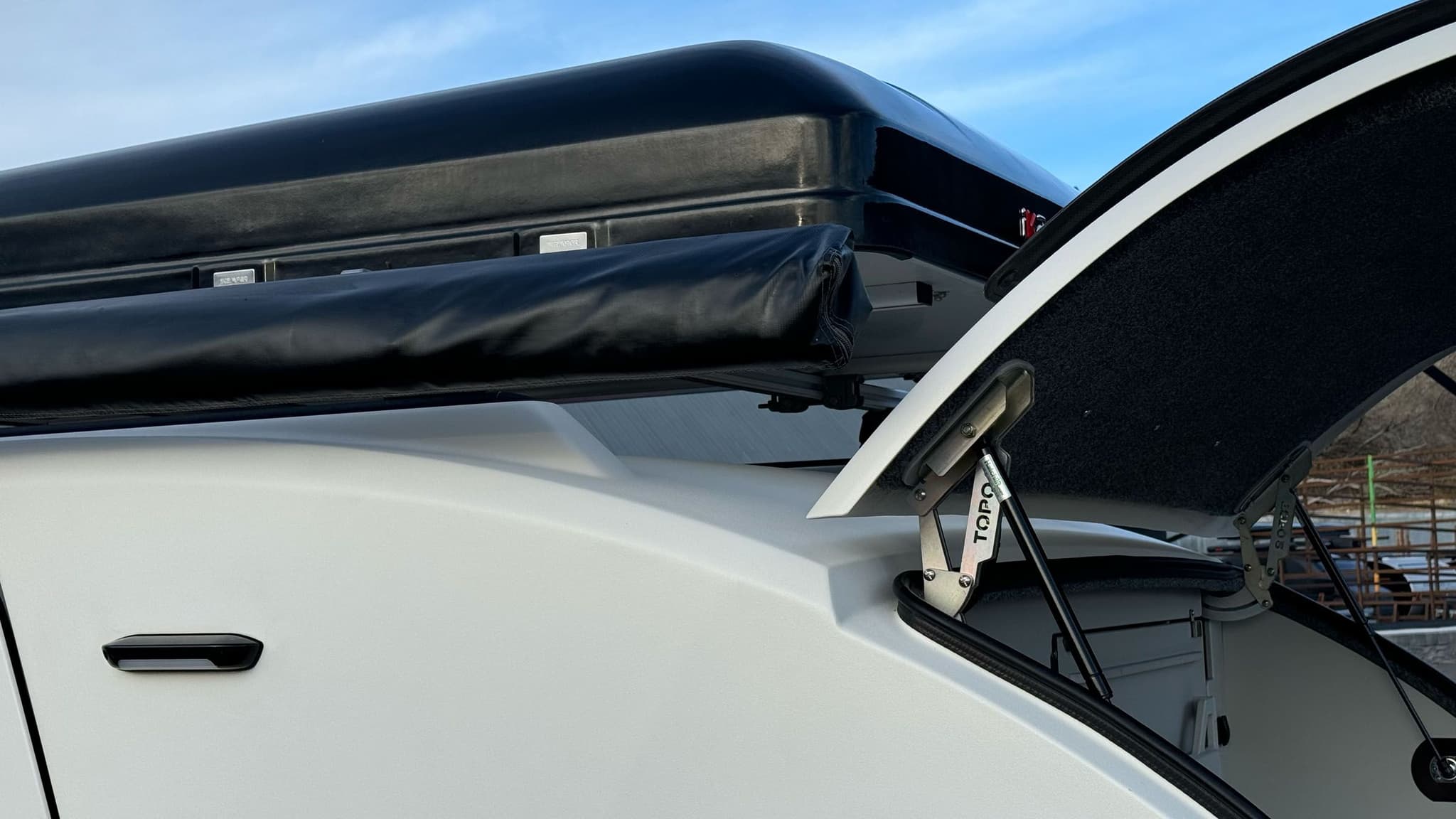 Exterior of a white 2023 Escapod TOPO2, photographed at Escapod's headquarters in Coalville, UT, with a ROAM awning and an iKamper Tent.