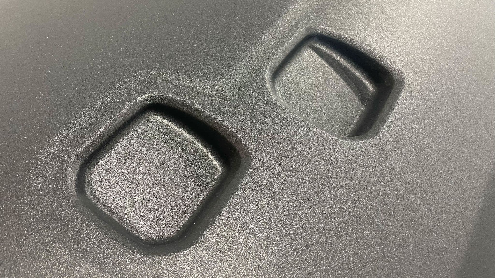 Close-up of a finished matte black Escapod trailer body, highlighting the textured fiberglass surface and recessed mounting points.