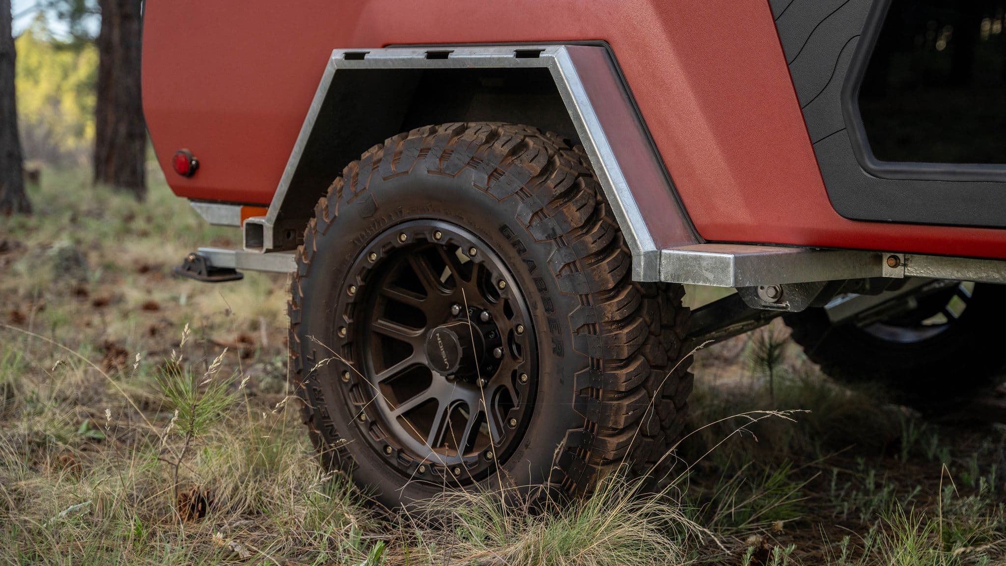 A close-up of the Escapod TOPO2’s off-road tire with deep treads, mounted under a sturdy metal fender.